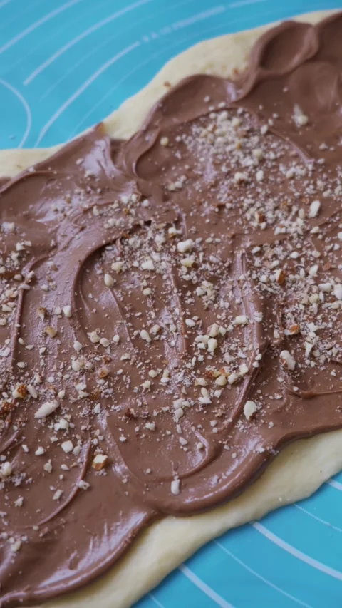 Spreading Chocolate Hazelnut Cream and Nuts on Dough for Sweet Muffins Stock Footage 334119815