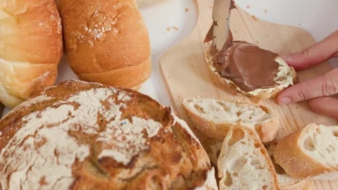 Spreading Chocolate Hazelnut Cream on Fresh Sliced Baguette Bread Stock Footage 337520062