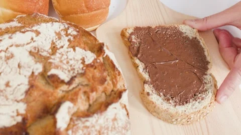 Spreading Chocolate Hazelnut Cream on Fresh Whole Wheat Sourdough Bread Stock Footage 337757834