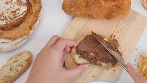 Spreading Chocolate Hazelnut Cream on Fresh Sourdough Bread Slice Stock Footage 337770630