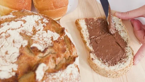 Spreading Chocolate Hazelnut Cream on Fresh Sourdough Bread Slice Stock Footage 337917932