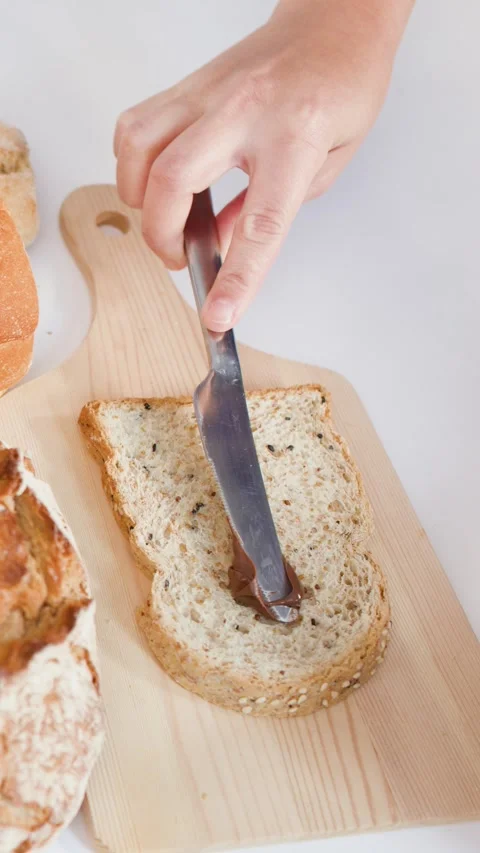 Spreading Chocolate Hazelnut Cream on Fresh Sliced Bread Stock Footage 337925919