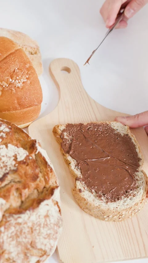 Spreading Chocolate Hazelnut Cream on Fresh Sourdough Bread Slice Stock Footage 338041765
