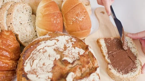 Spreading Chocolate Hazelnut Cream on Fresh Sliced Bread in Bakery Stock Footage 338421222