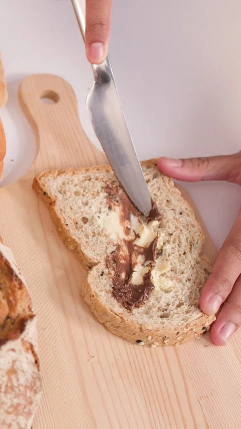 Spreading Chocolate Hazelnut Cream on Multigrain Bread Slice Stock Footage 337690944