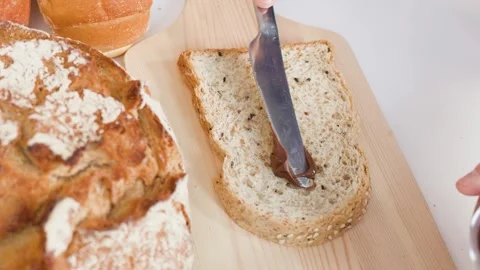 Spreading Chocolate Hazelnut Cream on Sliced Whole Grain Bread Stock Footage 337757786