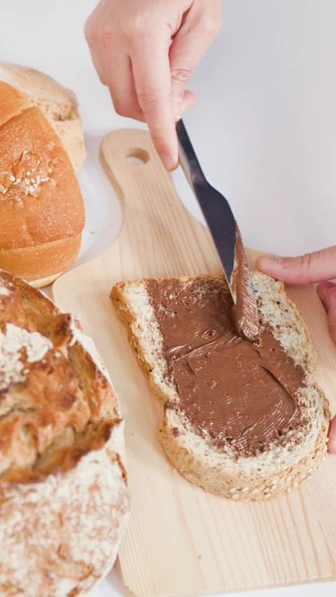 Spreading Chocolate Hazelnut Cream on Sourdough Bread Slice Stock Footage 337876853