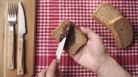 Spreading chocolate nut cream on a slice of freshly baked bread. Stockbeeldmateriaal 181007892
