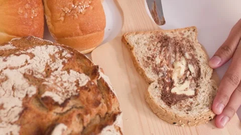 Spreading Chocolate Peanut Butter on Multigrain Bread Slice Video stock 337769061