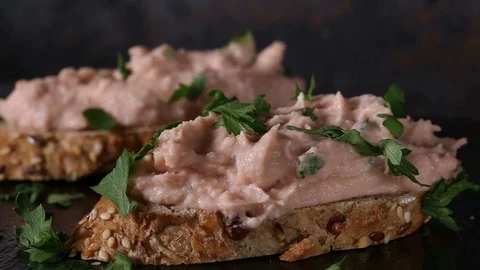 Spreading chopped parsley over two slices of bread with vegetable pate Stock Footage 98784419