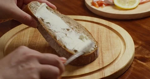 Spreading cream cheese on bread slice close up Vídeo Stock 327156705