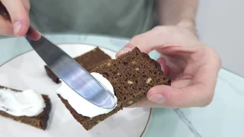 Spreading cream cheese on brown bread slice with a knife Video stock 282892557