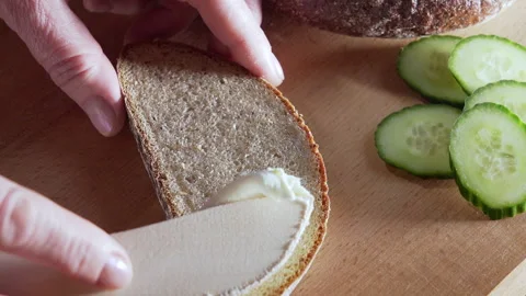 Spreading cream cheese on the dark bread with a wooden knife. Stock Footage 295380430
