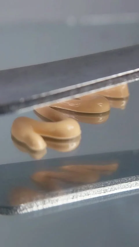 Spreading the cream evenly using a metal tool on a glass base. Vertical shoot Vídeos de archivo 329644035