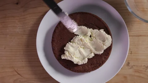 Spreading cream over a chocolate cake Stock Footage 64055415