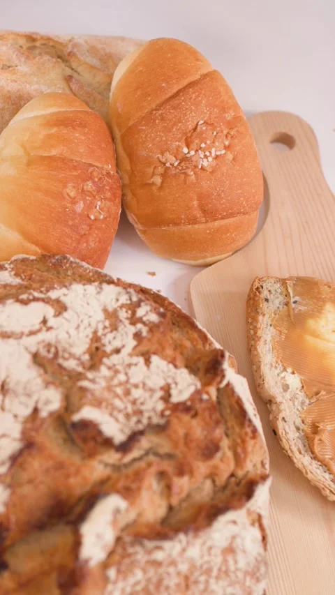 Spreading Creamy Peanut Butter on Multigrain Bread with Assorted Loaves Video stock 337748338