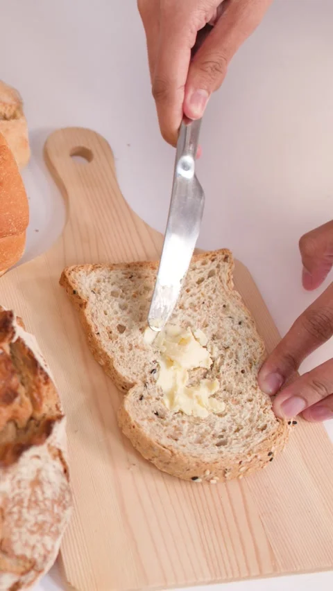 Spreading Creamy Peanut Butter on Multigrain Bread Slice Video stock 337996818