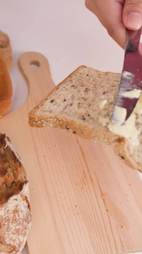 Spreading Creamy Peanut Butter on a Slice of Multigrain Bread Stock Footage 337520926