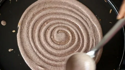 Spreading Finger millet batter on a griddle for crepes. The batter is evenly Stock-Footage 153617665