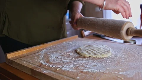 Spreading flour on a rolling pin surface with a hand above raw dough Vídeo Stock 128732248