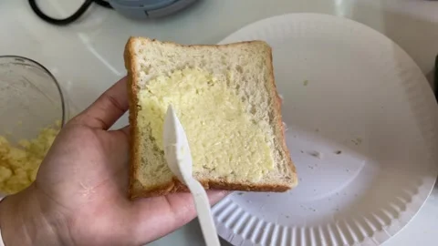 Spreading Garlic Butter Onto Sliced Bread With Plastic Spoon For Baking Stock Footage 334365279