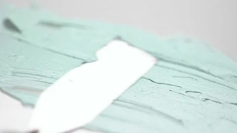 Spreading green clay mask over white surface with metal tool Stock Footage 170551504