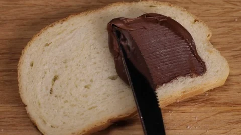 Spreading hazelnut chocolate spread on toasted bread Stock Footage 230178672