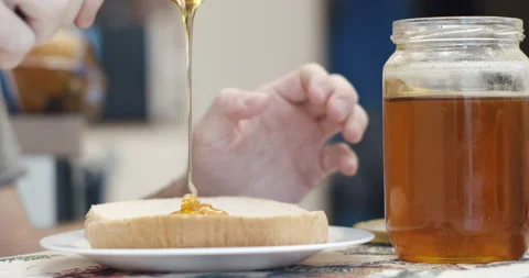 Spreading honey to a slice of bread - healthy breakfast Stock Footage 147338900