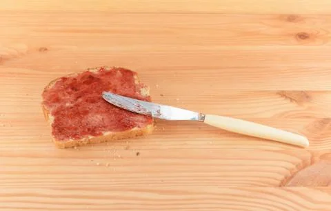 Spreading jam on fresh bread with a knife Stock Photos