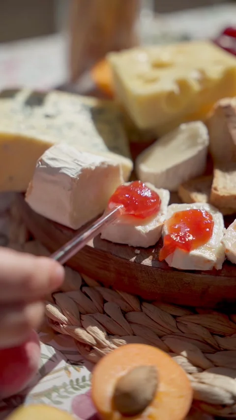 Spreading Jam Over a Slice of Soft Cheese on a Rustic Cheese Platter Vídeo Stock 281716507