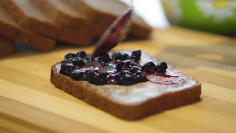 Spreading jam on rye bread with butter. Delicious and healthy breakfast. Video stock 246480656