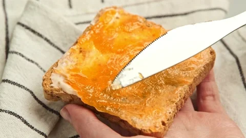 Spreading jam on on slice bread. Preparing tasty breakfast toast Stock Footage 144672475