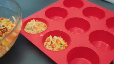 Spreading liquid cheese dough with vegetables in a muffin mold Stock-Footage 252235205