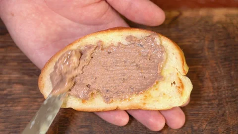Spreading liver pate on bread in kitchen Stock Footage 254079870
