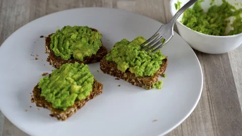 Spreading mashed avocado on toast and sprinkle with salt and spices. Healthy Stock Footage 104657572