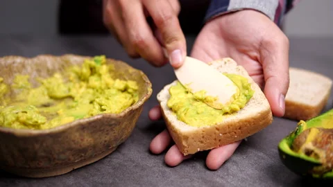 Spreading Mashed Avocado On Toast. Healthy Vegan Breakfast. Cooking healthy food Stock Footage 137285644