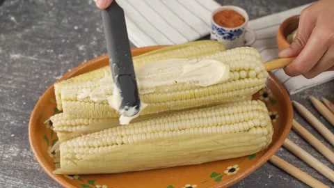 Spreading mayonnaise on cooked corn, A typical Mexican snack in September Stock Footage 280316878