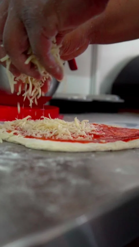 Spreading mozzarella cheese over pizza dough Stock Footage 298724714