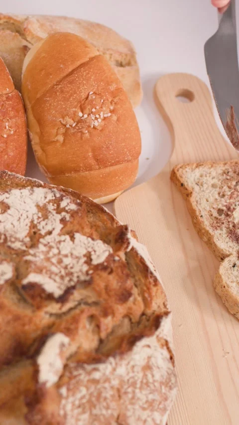 Spreading Nut Butter on Multigrain Bread with Assorted Bakery Loaves Video stock 337747123