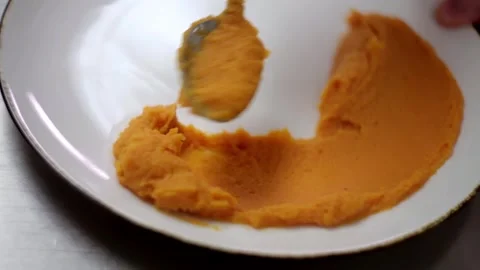 Spreading orange paste in a white plate Stock Footage 307340059