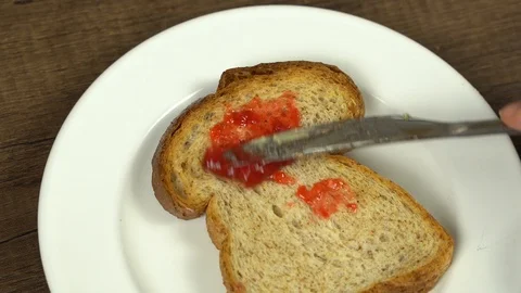 Spreading organic fresh strawbery jam on baked whole wheat bread Stock Footage 113074870