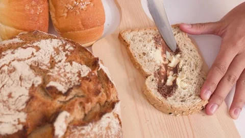 Spreading Peanut Butter on Multigrain Bread Slice Video stock 338421020