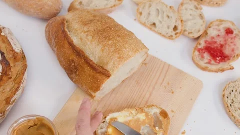 Spreading Peanut Butter on Sliced Artisan Sourdough Bread for Breakfast Stock Footage 337395024