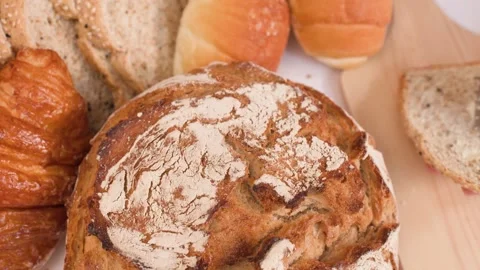 Spreading Peanut Butter on Sourdough Slice with Assorted Bakery Breads Stock Footage 337532907
