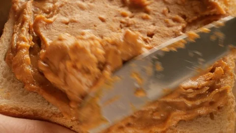 Spreading peanut butter on toasted bread, making sandwich Видео 125161552