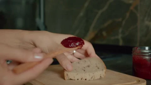 Spreading raspberry jam on a slice of bread in a modern kitchen 스톡 동영상 320951961