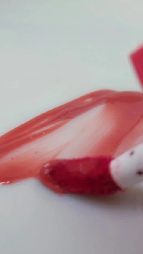 Spreading red lip tint liquid evenly on a white surface using a brush. Abst.. Stock Footage 332227144