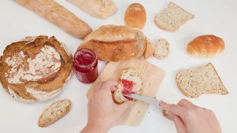 Spreading Red Strawberry Jam on Sourdough Bread Slice Overhead View Stockbeeldmateriaal 337518974