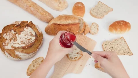 Spreading Red Strawberry Jam on Sourdough Bread with a Knife Stock Footage 337519502