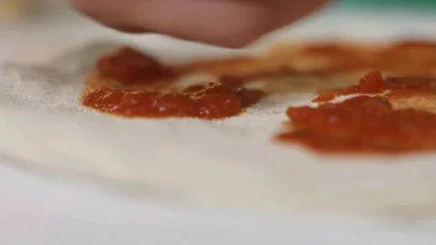 Spreading red tomato sauce on thin dough with spoon Video stock 333835167